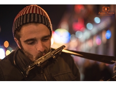 Forrest wails on his harmonica while playing acoustic guitar.